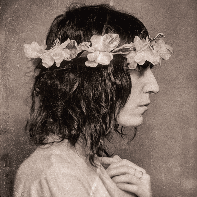 Side view of a long haired person wearing a crown of flowers.